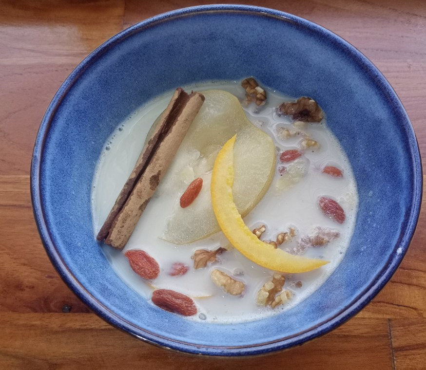 Warming poached pear and ginger oats with walnuts and goji berries