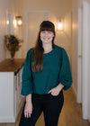 Gold Coast Naturopath hayley Brass in Vyne Health hallway having photo shoot with green top and black pants with hallway hampton lighting and flowers in background
